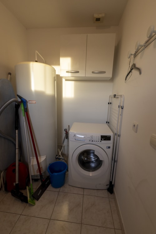 Buanderie du gîte Accolade avec machine à laver, chauffe-eau et produits d'entretien à Châteaudun