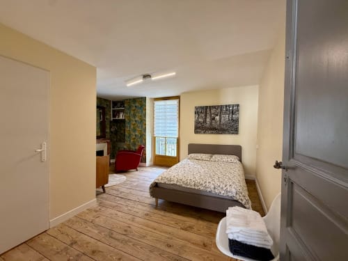 Przestronna sypialnia w cottage w Lourdes z widokiem na ogród, łóżko queen-size, żółte ściany, drewniane podłogi, biurko i dostęp do balkonu