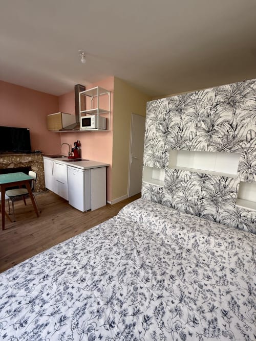 Przytulne studio w Lourdes z dekoracyjną pościelą, różową kuchenką i botaniczną tapetą