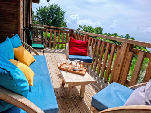 Colorful seaside bungalow deck at Le Bougainvillier Blanc with loungers, cushions, and wooden railings overlooking tropical