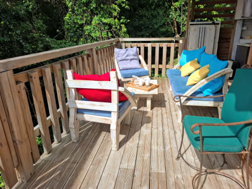 Muebles de terraza y cojines coloridos sobre la terraza de madera del bungalow Le Bougainvillier Blanc en Pointe-Noire