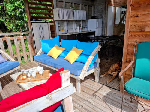 Área de descanso colorida en el bungalow Le Bougainvillier Blanc con asientos con cojines azules y rojos, almohadas amarillas