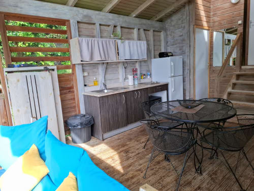 Cocina abierta y comedor con acentos azules, decoración de madera y zona de asientos exterior en Le Bougainvillier Blanc