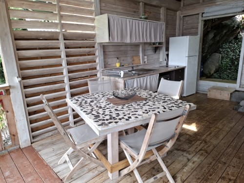 Área de comedor y cocina al aire libre en Le Bougainvillier Blanc en Pointe Noire con terraza de madera, mesa con patrón y