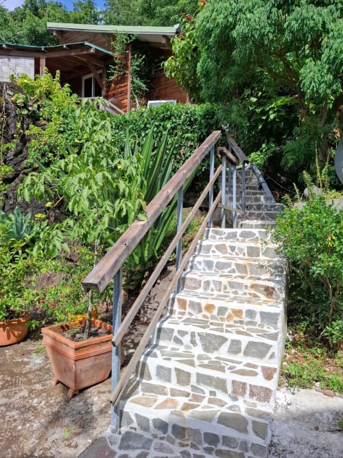 Camino de piedra con barandales de madera que conduce al Bungalow 3 de Le Bougainvillier Blanc en Pointe-Noire, rodeado de exuberante vegetación