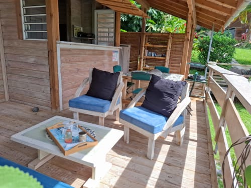 Wooden bungalow terrace at Le Bougainvillier Blanc with lounge chairs, blue cushions, and coffee table overlooking garden in