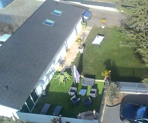 Vue aérienne du jardin du gîte Le Miroir avec terrasse, pelouse et voitures garées à Domérat
