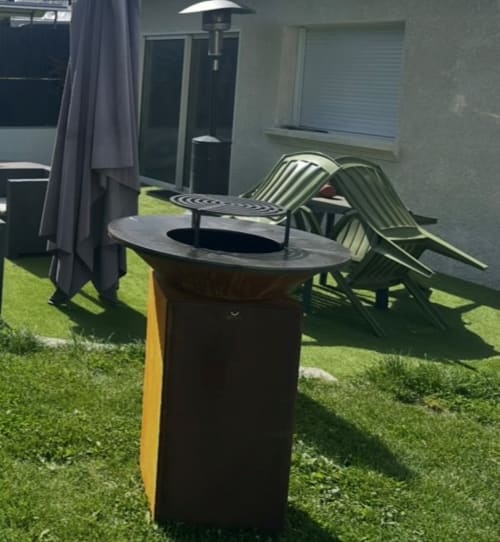 Espace détente extérieur avec table foyer, chaises longues vertes et chauffage de patio au Gîte du Miroir