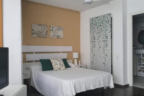 Estudio moderno frente al mar en MiramaRent, Benicàssim con cama blanca, muro color arena y vistas al océano