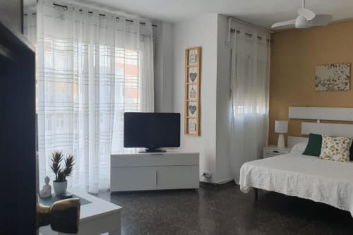 Moderno estudio frente al mar en Benicàssim con TV, cama y vistas al océano a través de cortinas translúcidas