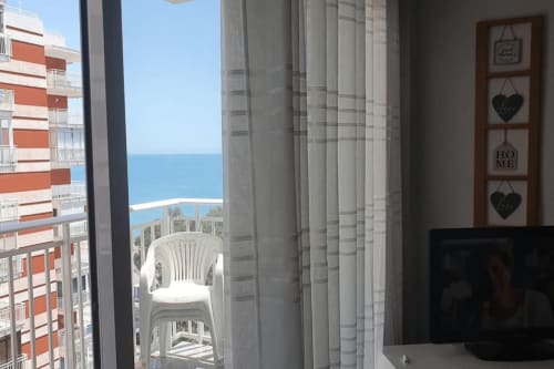 Apartamento frente al mar en Benicàssim con vistas al océano desde el balcón, silla blanca, mar visible más allá del edificio
