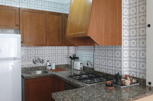 Cocina completamente equipada con estufa de gas, encimeras de granito, armarios de madera y decoración patterned en apartamento frente al mar en Benicàssim