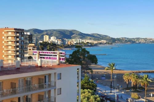 Apartamento frente al mar en Benicàssim con vistas al océano, palmeras y costa mediterránea con montañas