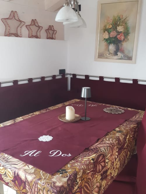 Tavolo da pranzo dell'appartamento Al Dos a Livigno con tovaglia bordeaux, candela e viste montane