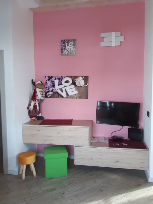 Camera moderna ad Al Dos Livigno con parete rosa, scrivania in legno, TV e vista montagna