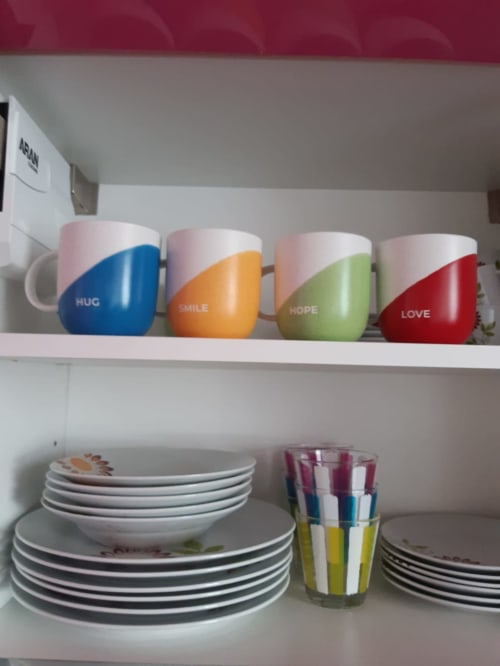 Coloratissime stoviglie e tazze esposte su mensole bianche nella cucina dell'appartamento Al Dos a Livigno