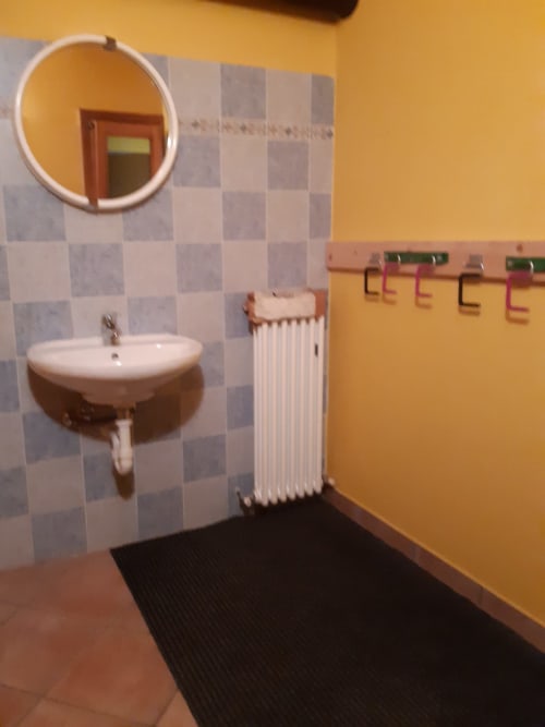 Bagno luminoso dell'appartamento Al Dos a Livigno con specchio rotondo, lavabo sospeso, radiatore e rivestimento con piastrelle a quadri