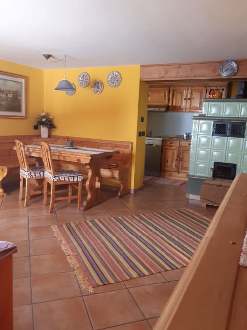Ampia cucina e zona pranzo ad Al Dos, Livigno con pareti gialle, mobili in legno e tappeto a righe