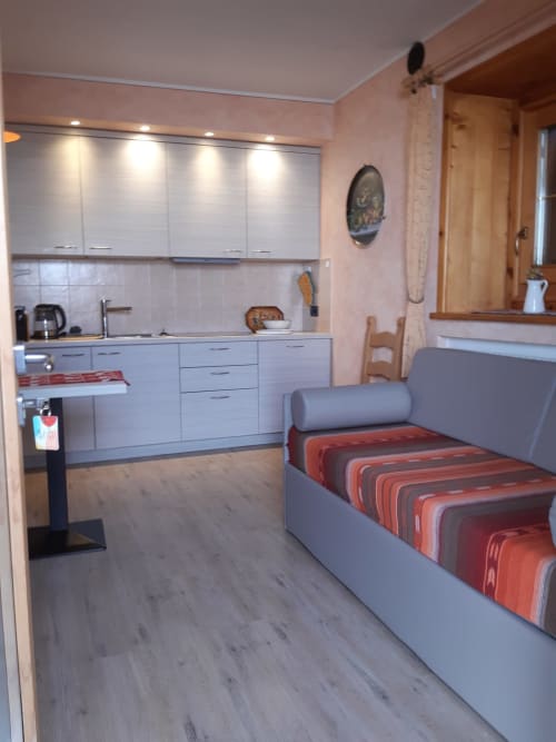 Appartamento Al Dos a Livigno con cucina moderna, letto grigio con biancheria a righe rosse e pavimentazione in legno