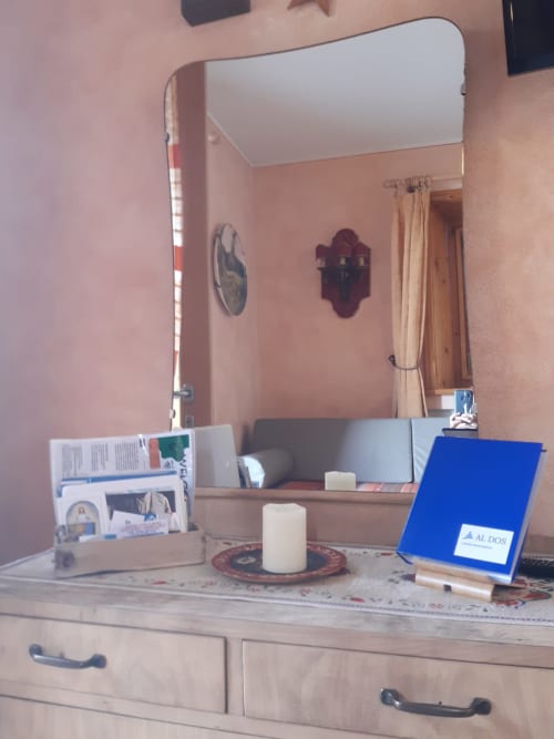 Vanity dell'appartamento Al Dos con specchio, candela e cartella di benvenuto blu a Livigno
