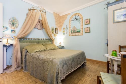 Camera elegante con letto a baldacchino presso Dormire Assisi B&B ad Assisi, Italia, con arredamento d'epoca e pareti blu chiaro
