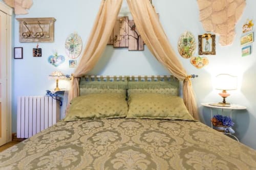 Elegante letto a baldacchino con biancheria verde presso Dormire Assisi, affascinante B&B ad Assisi, Italia, decorato con opere d'arte vintage.