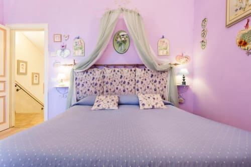 Camera da letto rosa con letto a baldacchino presso Dormire Assisi B&B, con decorazioni floreali e accenti viola ad Assisi.