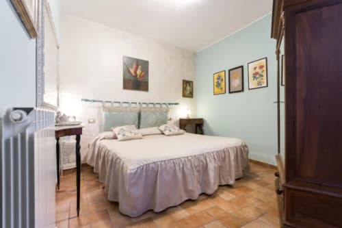 Accogliente camera da letto presso il Dormire Assisi B&B di Assisi con pareti verde menta, letto in legno e opere d'arte floreali
