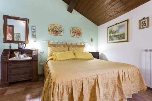 Camera accogliente al Dormire Assisi B&B con letto giallo, soffitto in legno e pareti verde menta