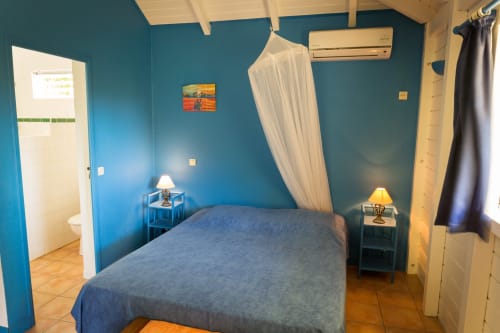 La jolie chambre BleuRoi climatisée avec un lit de 160cm et moustiquaire, pour 2 à 4 personnes, aux gîtes Les Jardins de l'espérance à Bouillante en Guadeloupe
