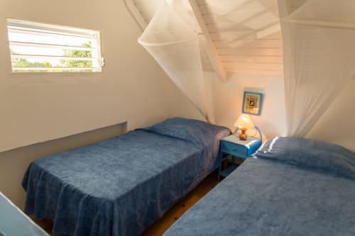 La mezzanine climatisée avec 2 lits simples et moustiquaires dans la location BleuRoi 2 à 4 personnes, aux jardins de l'espérance, référencé 2 étoiles, à Malendure/Bouillante, en Guadeloupe