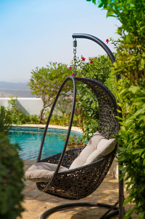 Silla colgante tejida en negro con cojines con vistas a la piscina en La Vista Medina Stays, Medina Sidonia