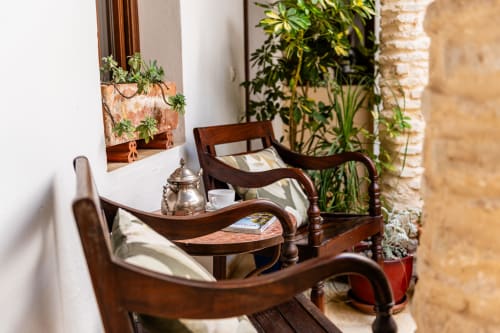 Acogedora zona de estar en el patio de La Vista Medina Stays con sillas de madera, plantas en macetas y decoración tradicional en Medina