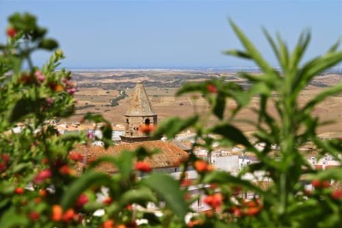 Torre campanario de Medina Sidonia con flores rojas y vistas al paisaje rural desde La Vista Medina Stays