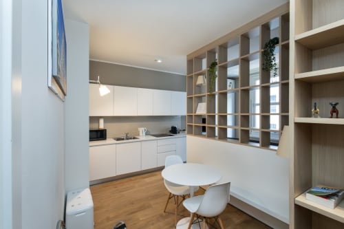 Moderne Küchen-Essbereich im Magnolia Apartments Milan mit weißem Mobiliar, Holzregalen, rundem Tisch und Stadtblick