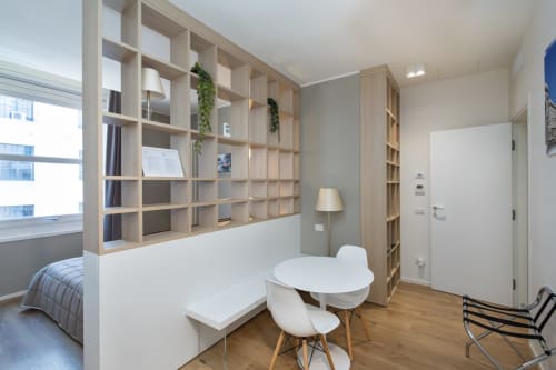 Modernes Studio im Magnolia Apartments Mailand mit Holzregalen, weißen Möbeln, Esstisch und Stadtblick