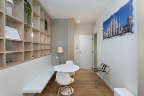 Modernes Wohnzimmer im Magnolia Apartments Milan mit Holzregalen, weißem Rundtisch und Stadtfotografie