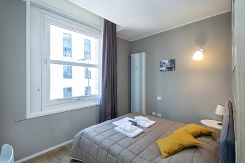Modernes Schlafzimmer in den Magnolia Apartments Mailand mit Stadtblick, gelben Kissen und zeitgenössischen Möbeln