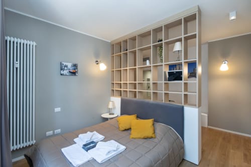 Modernes Schlafzimmer in den Magnolia Apartments Mailand mit eingebauten Regalen, gelben Kissen und Stadtblick
