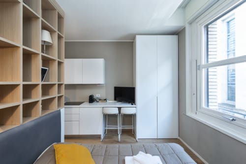 Modernes Studio in den Magnolia Apartments Mailand mit Holzregalen, weißen Möbeln, Arbeitsbereich und Stadtblick
