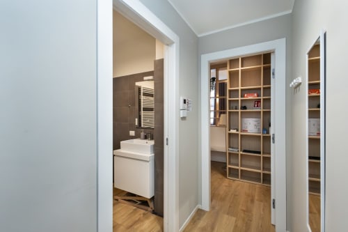Moderner Flur in Mailänder Wohnung mit Badezimmer, hölzernem Regal und Parkettboden