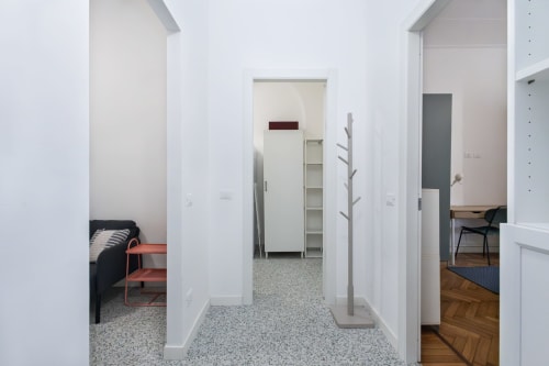 Pasillo luminoso en Apartamentos Magnolia Milán conectando varias habitaciones con paredes blancas y suelos de terrazo