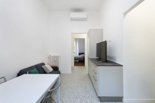 Moderno estudio en Milán con cocina americana, sofá y vista al jardín desde la puerta