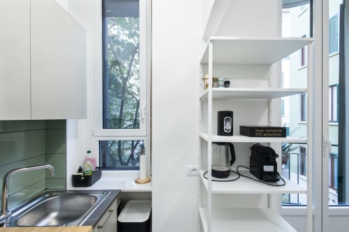 Cocina moderna con estantería blanca que exhibe una tetera y electrodomésticos, fregadero, ventana con vista al jardín en Magnolia