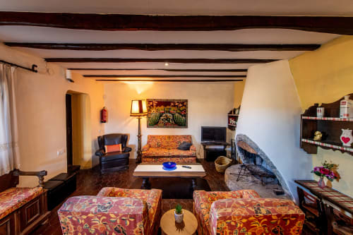 Salón rústico en Masia Rural Ca l'Eloi Janet de Barcelona con vigas vistas, mobiliario colorido y decoración tradicional