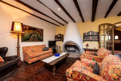 Sala de estar rústica en Masia Rural Ca l'Eloi Janet con sofás estampados, chimenea y vigas vistas