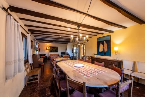 Amplio comedor en Masia Rural Ca l'Eloi Janet de Barcelona con vigas de madera, elegante mesa y paredes amarillas.