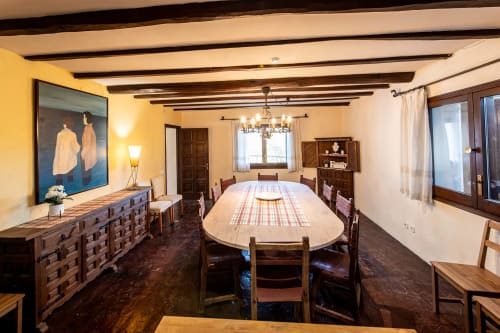 Comedor espacioso en la Masía Rural Ca l'Eloi Janet cerca de Barcelona con vigas de madera, mesa ovalada y decoración rústica