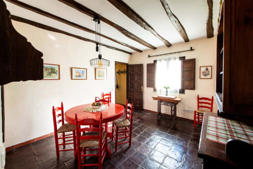 Comedor rústico con sillas rojas, mesa redonda y vigas de madera vista en Masía Rural Ca l'Eloi Janet cerca de Barcelona