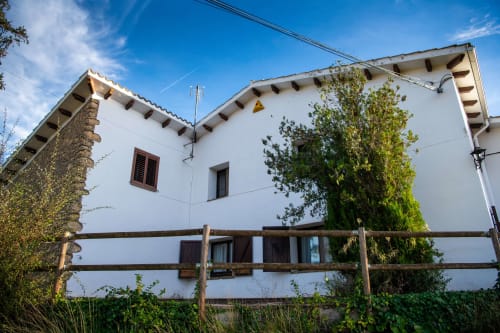 Masía Rural Ca l'Eloi Janet, casa de campo con muros blancos, valla de madera y hiedra en la campiña de Barcelona